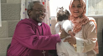 Presiding Bishop Michael Curry hands a toddler back to her mother