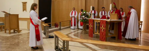 Revd Charlotte stands facing the bishop and clergy in front of the altar