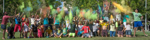 Young people in a group photo with colour dust bombs thrown over them