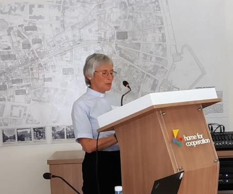Anne Futcher speaking at the forum in front of a large map of the area