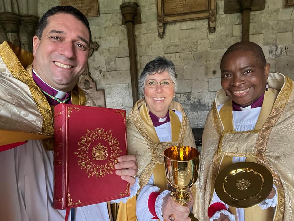 Archbishop Hosam holding the bible and Bishop Guli Francis-Dehqani holding the chalice and another bishop holding the plate