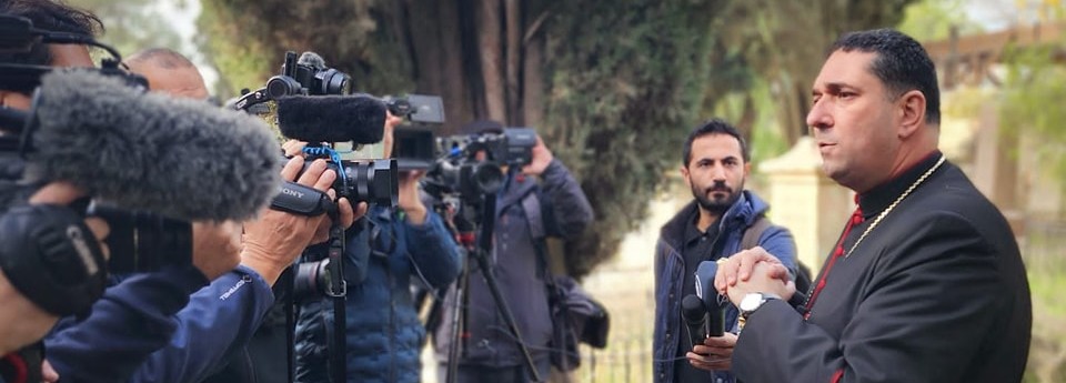 The Archbishop talking to the Press, who have cameras and microphones, in the cemetery