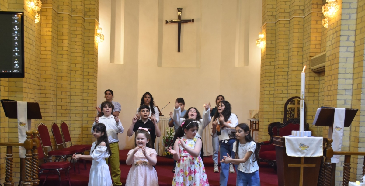 Children singing, clapping and doing actions at the front of the church during the service