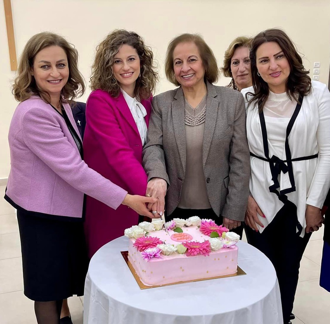 Mrs Naoum, Mrs Diab cutting the cake surrounded by other ladies in attendance