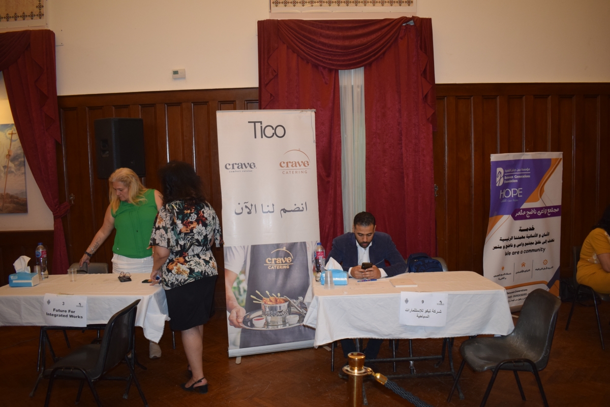 People standing and sitting around two tables with a poster for Crave catering; one of the companies that are looking to recruit with people