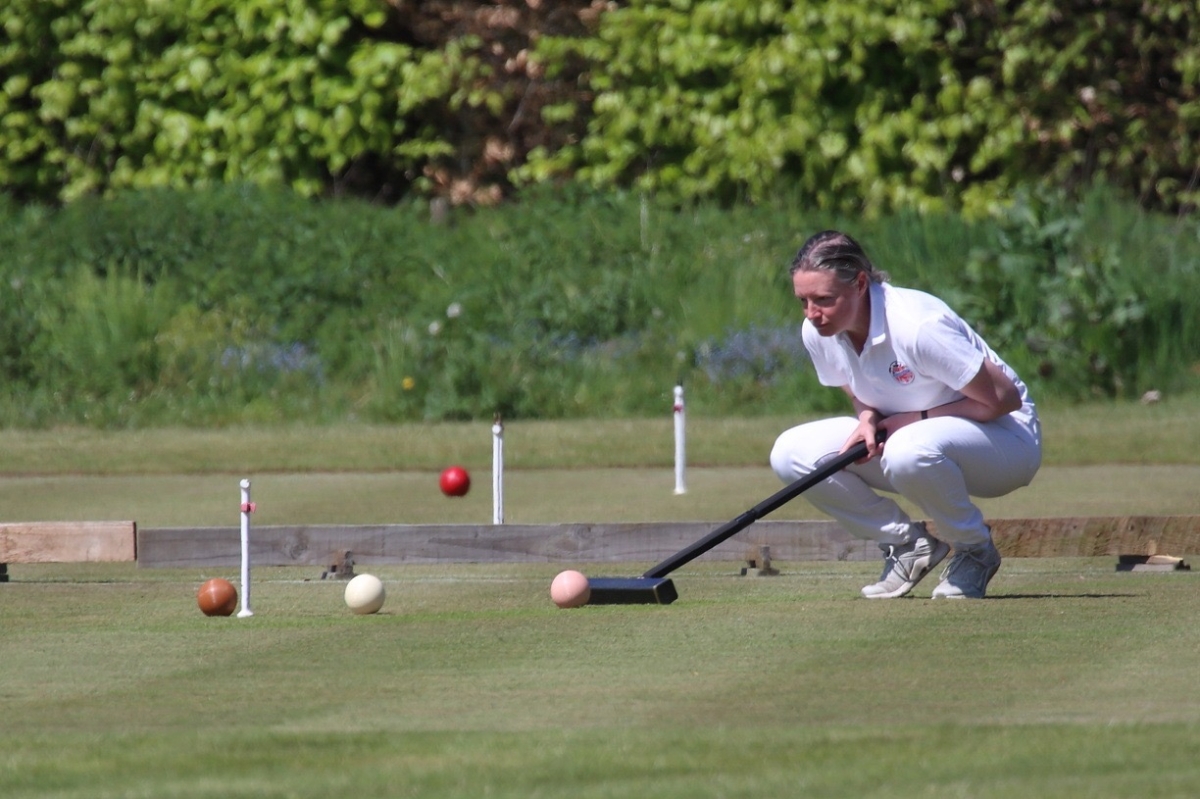 Gabrielle eyeing up a hoop on a croquet lawn