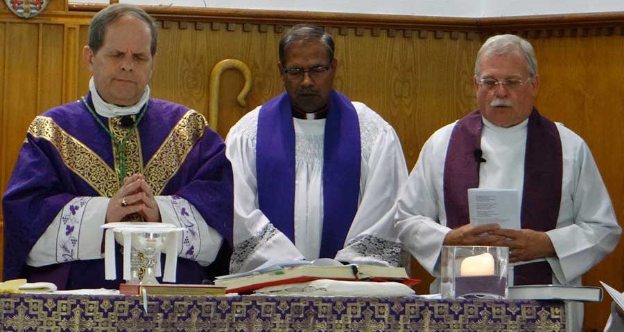Archbishop Michael, Canon Harrison and Archdeacon Bill Schwarz praying behind the alter and holy sacrements