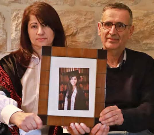 Layan's family hold her picture as they wait and pray