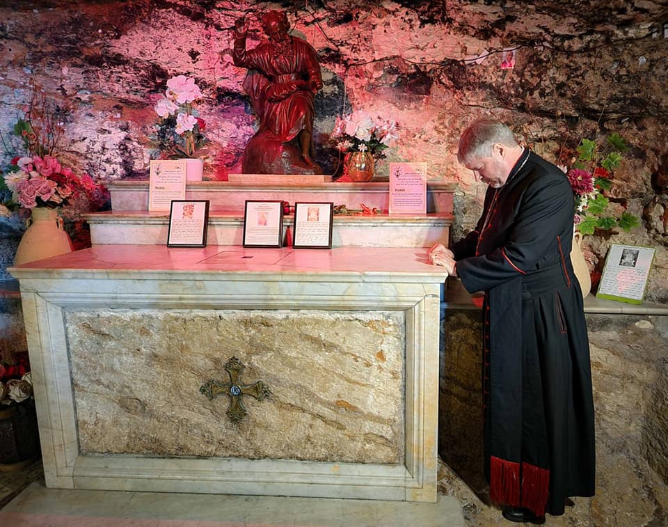 The Reverend canon Don Binder standing to the side of the altar with head bowed in prayer