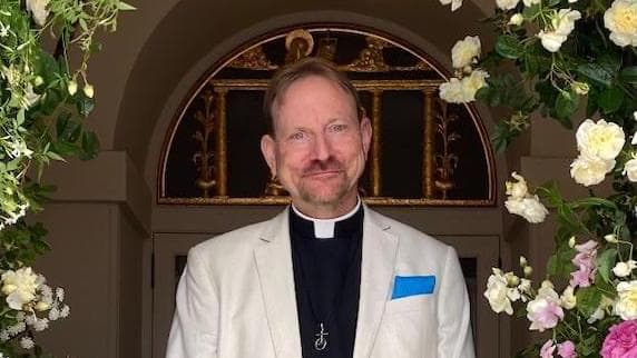 The Reverend Dr Richard Fermer in an archway of flowers