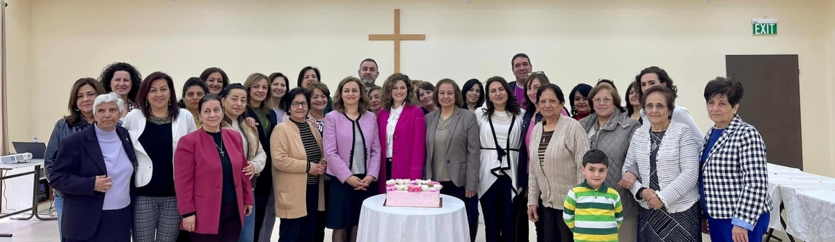 The whole group standing behind the table with the cake