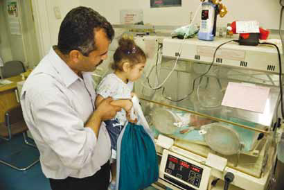 A father and his daughter visit their new born, who is in an incubator in the neonatal unit